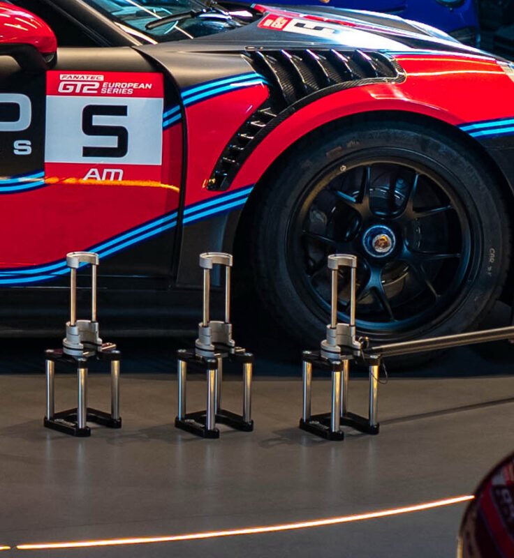 NP air jack safety stands in front of GT12 European Series Porsche race car – motorsport pit lift equipment
